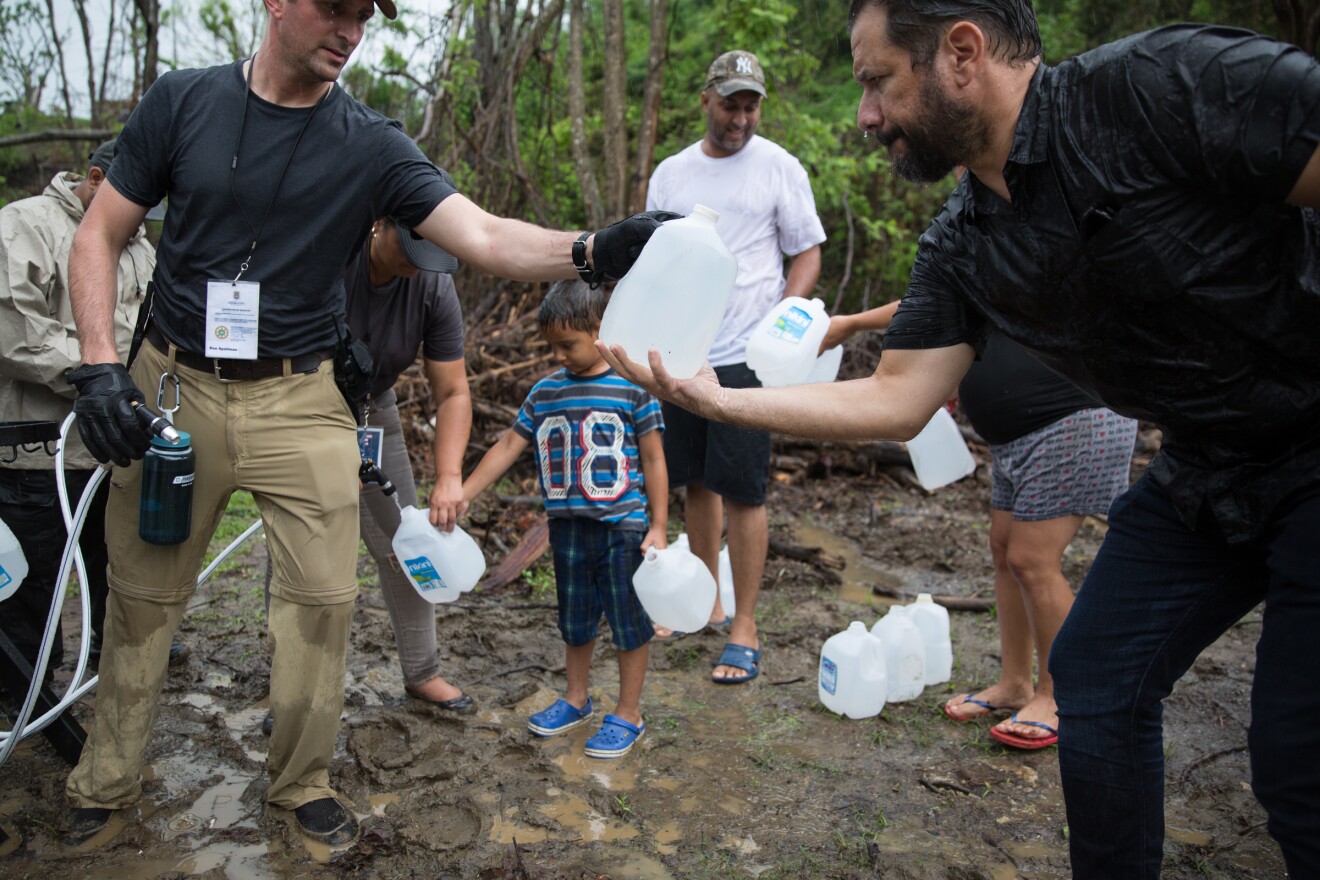 Salinas residents wait in line for water. They haven't had much access to clean water since the hurricane hit the island weeks ago.